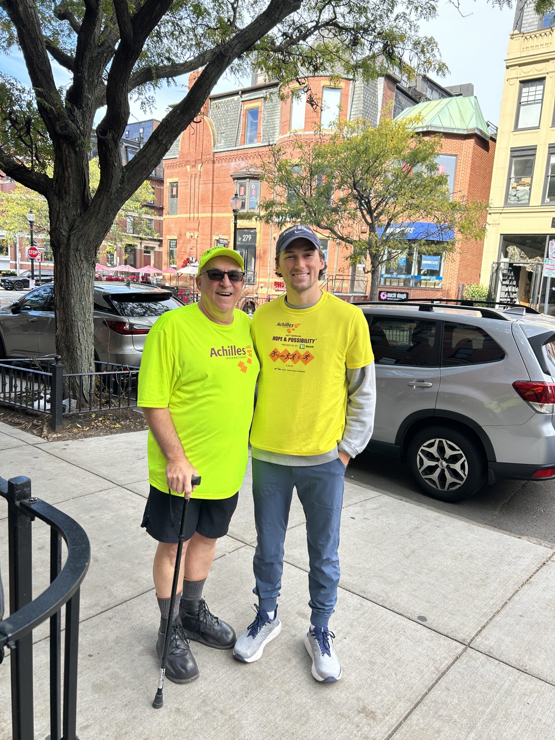 two people in yellow shirts standing next to a tree
