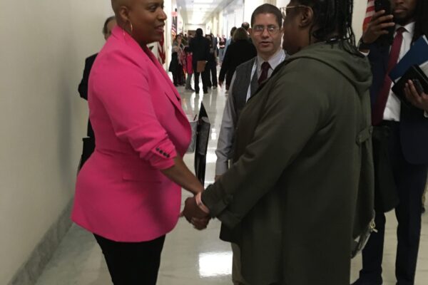 Congresswoman Ayanna Pressley holds hands with Lisa Sims