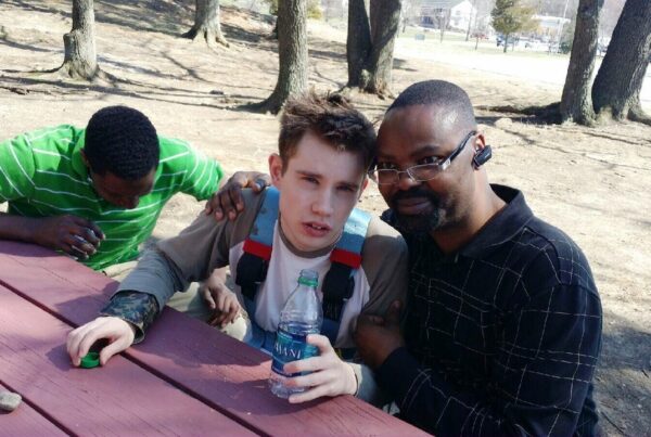 three men sitting at a picnic table posing for the camera