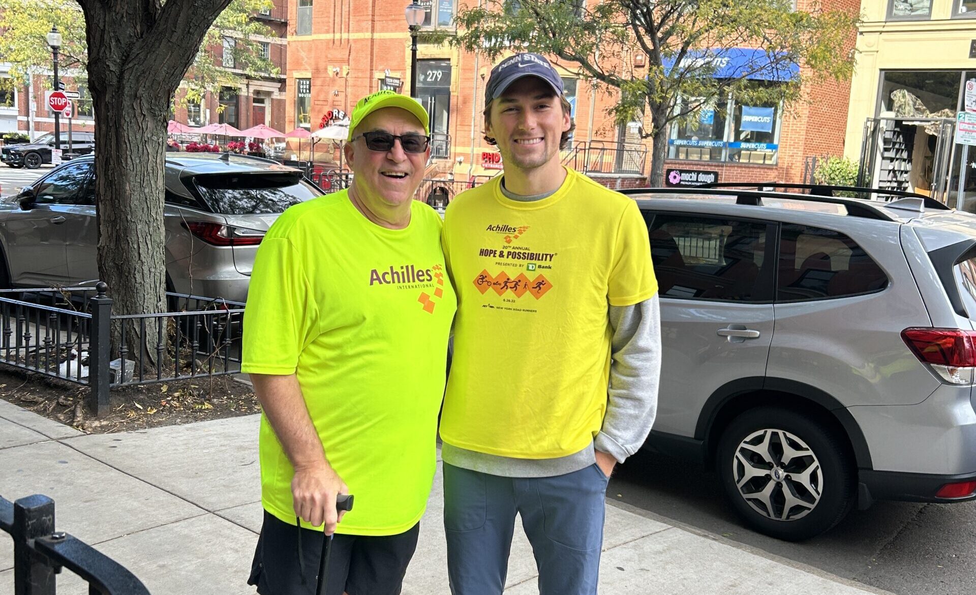 two people in yellow shirts standing next to a tree