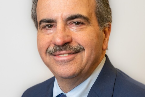 a man in a suit and tie smiling at the camera