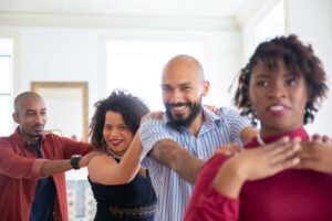 Four people holder each other's shoulders and dancing