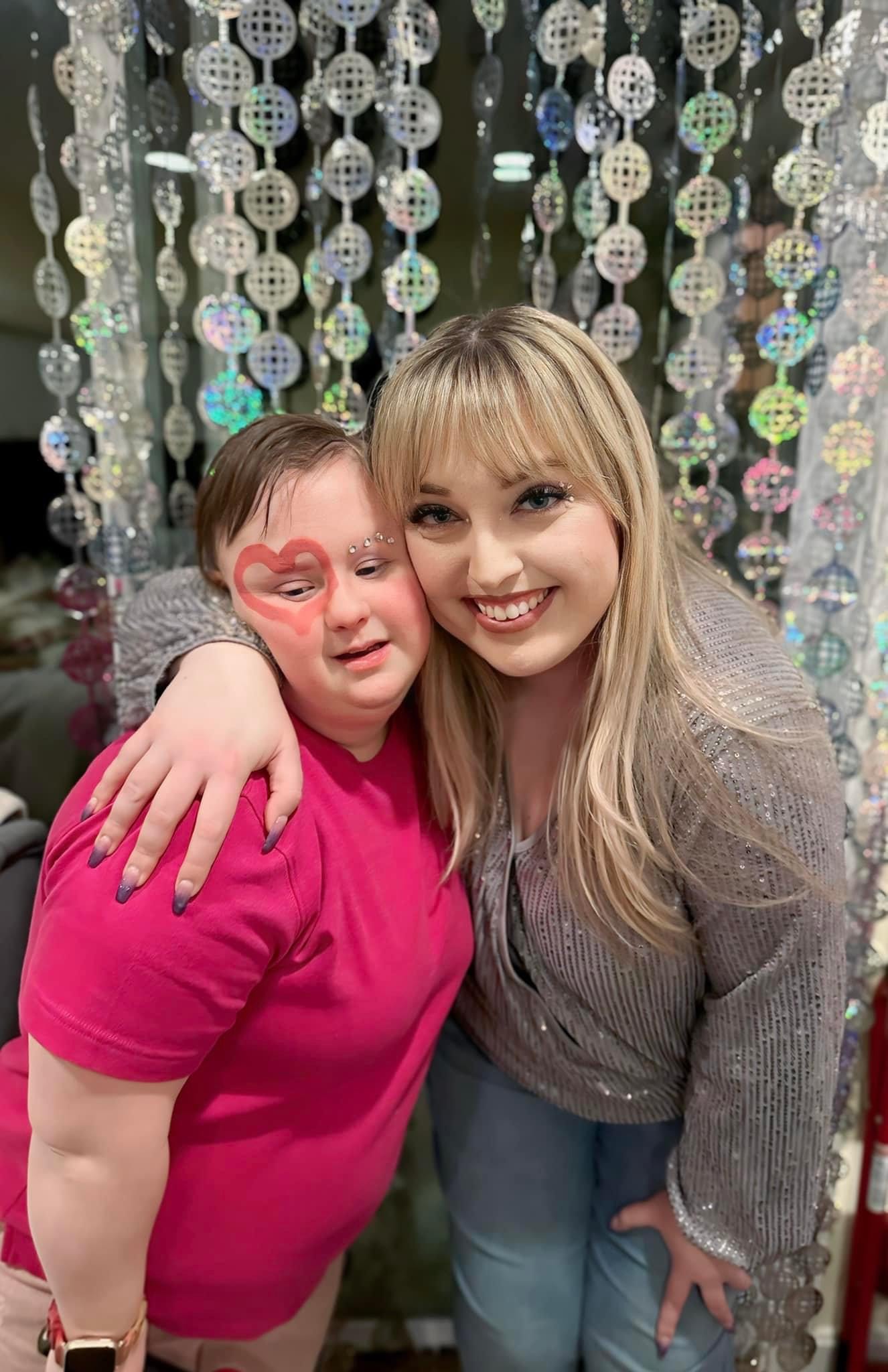 Two women hugging in front of a sparkly curtain