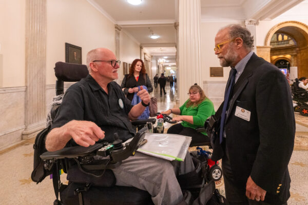 a man in a wheelchair talking to another man in a suit