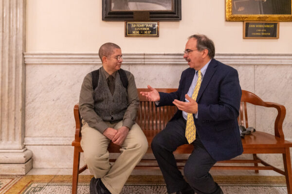 two men sitting on a bench talking to each other