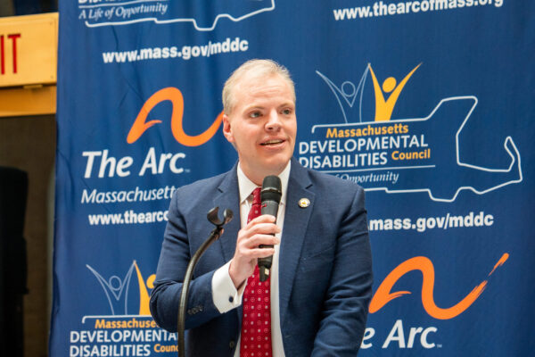 a man in a suit and tie speaking into a microphone