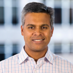a man in a checkered shirt smiles at the camera