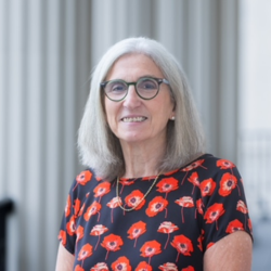a woman with grey hair and glasses standing in a room