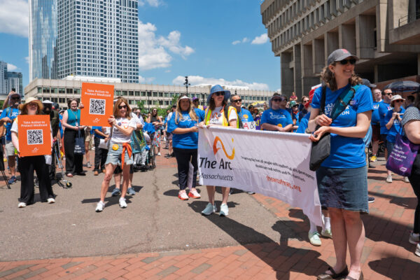 a group of people standing on a street holding a banner