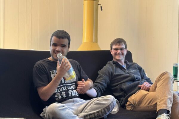 two men sitting on a couch with drinks in their hands