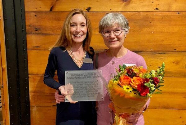 two women standing next to each other holding a bouquet of flowers