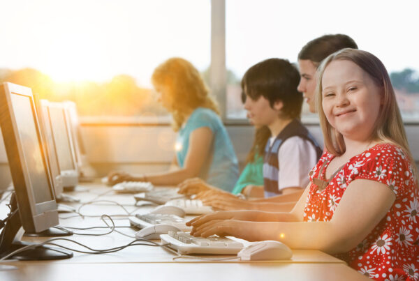 a group of children sitting at a computer desk