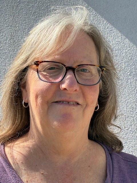 a woman wearing glasses standing in front of a wall
