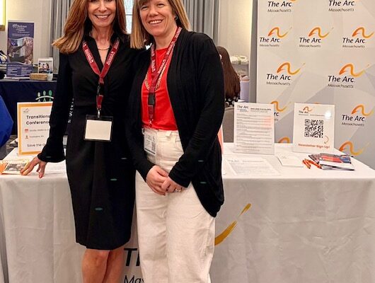 two women standing next to each other in front of a table