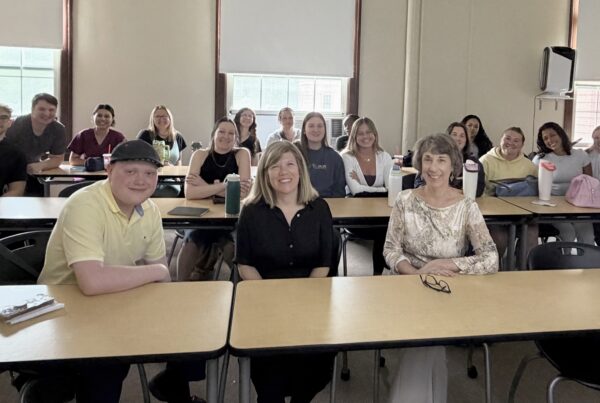 a group of people sitting at desks in a classroom