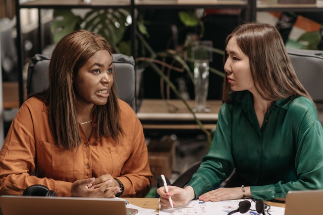 Two women sitting at a desk and working together