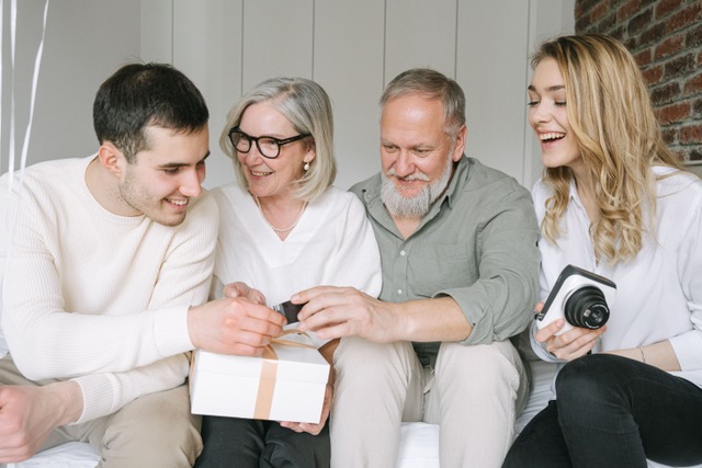 4 family members smiling and passing a gift