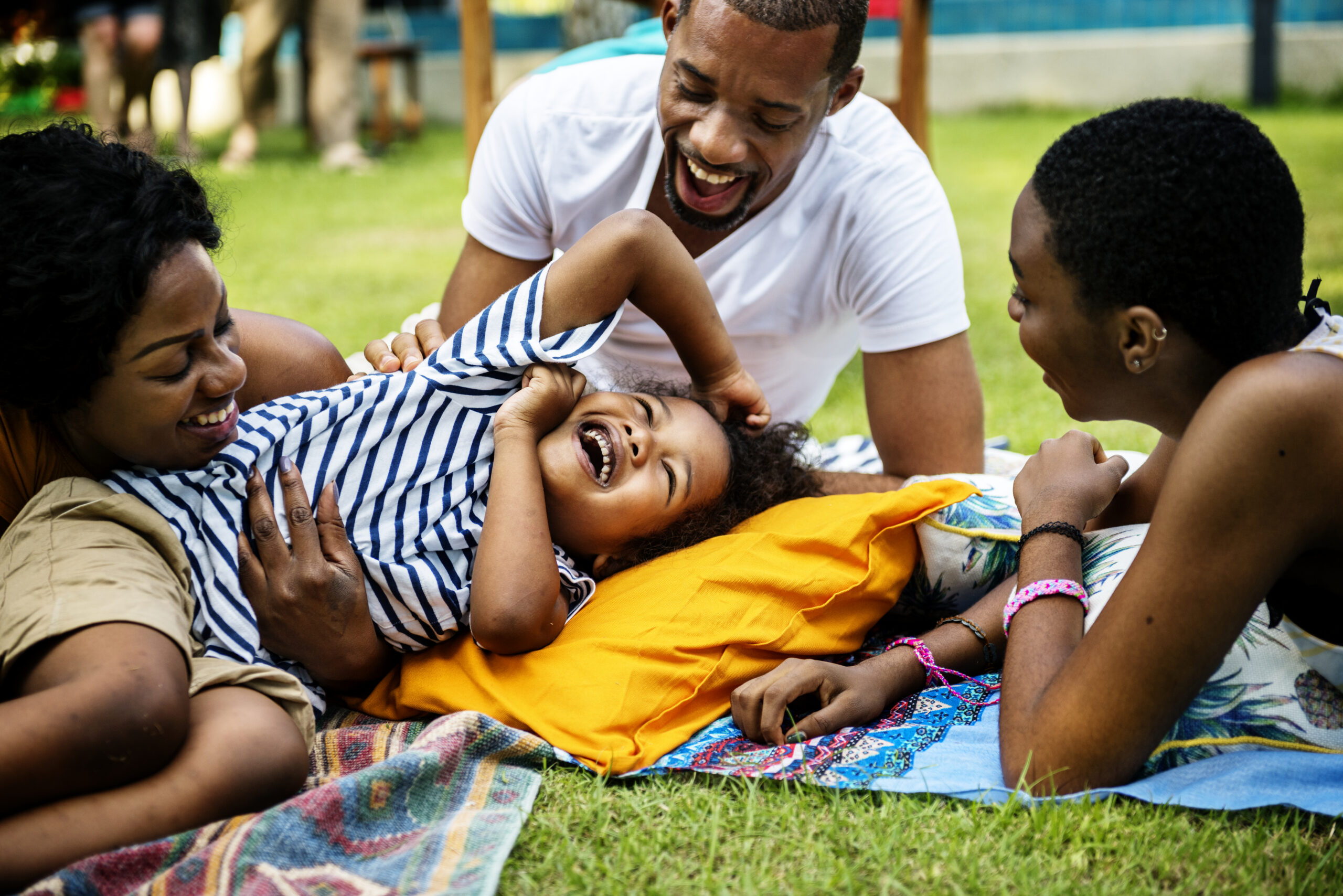 Two parents and two children lying on the grass together and laughing