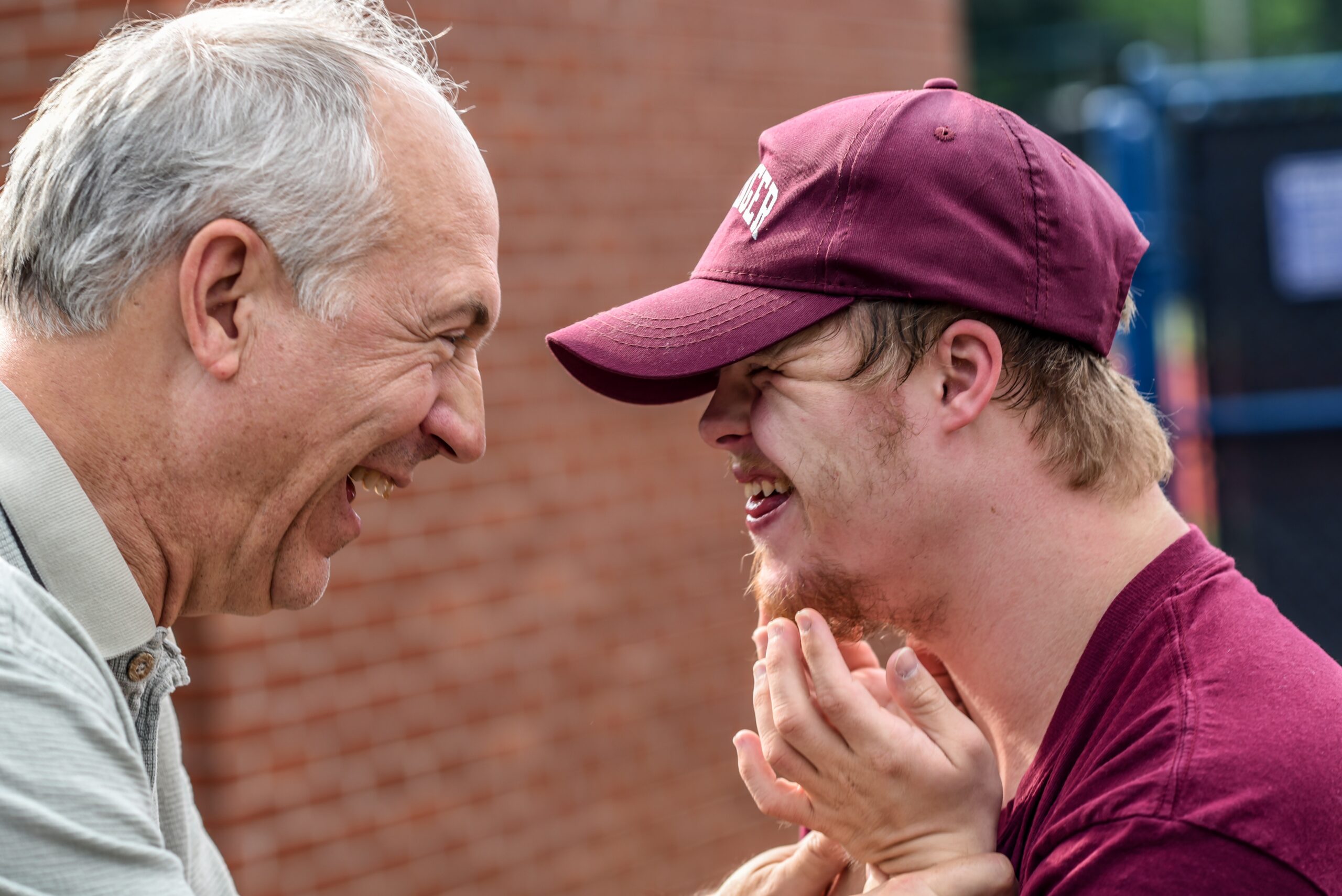 An older and younger man facing each other and grinning