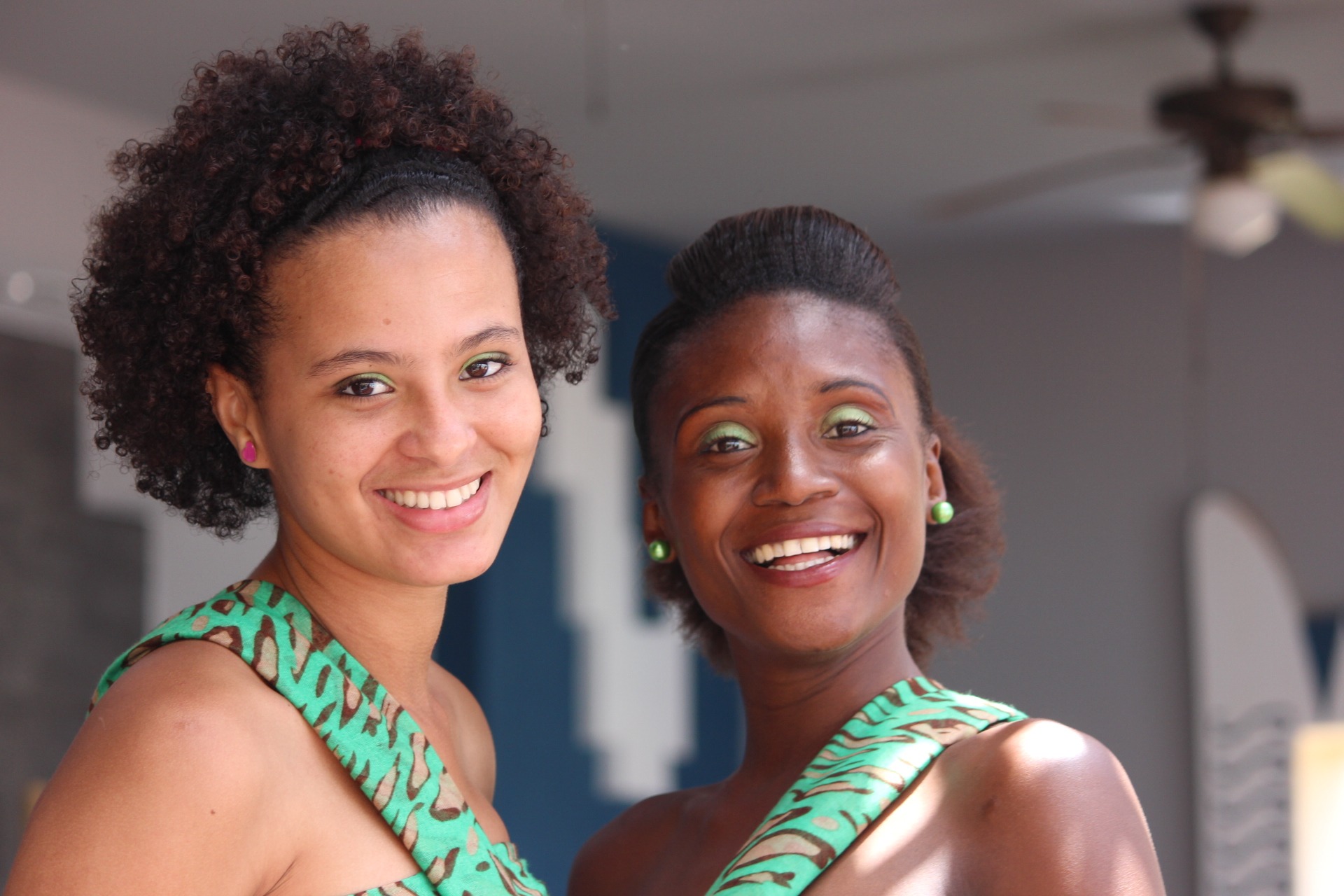 Two women in green and brown dresses smiling